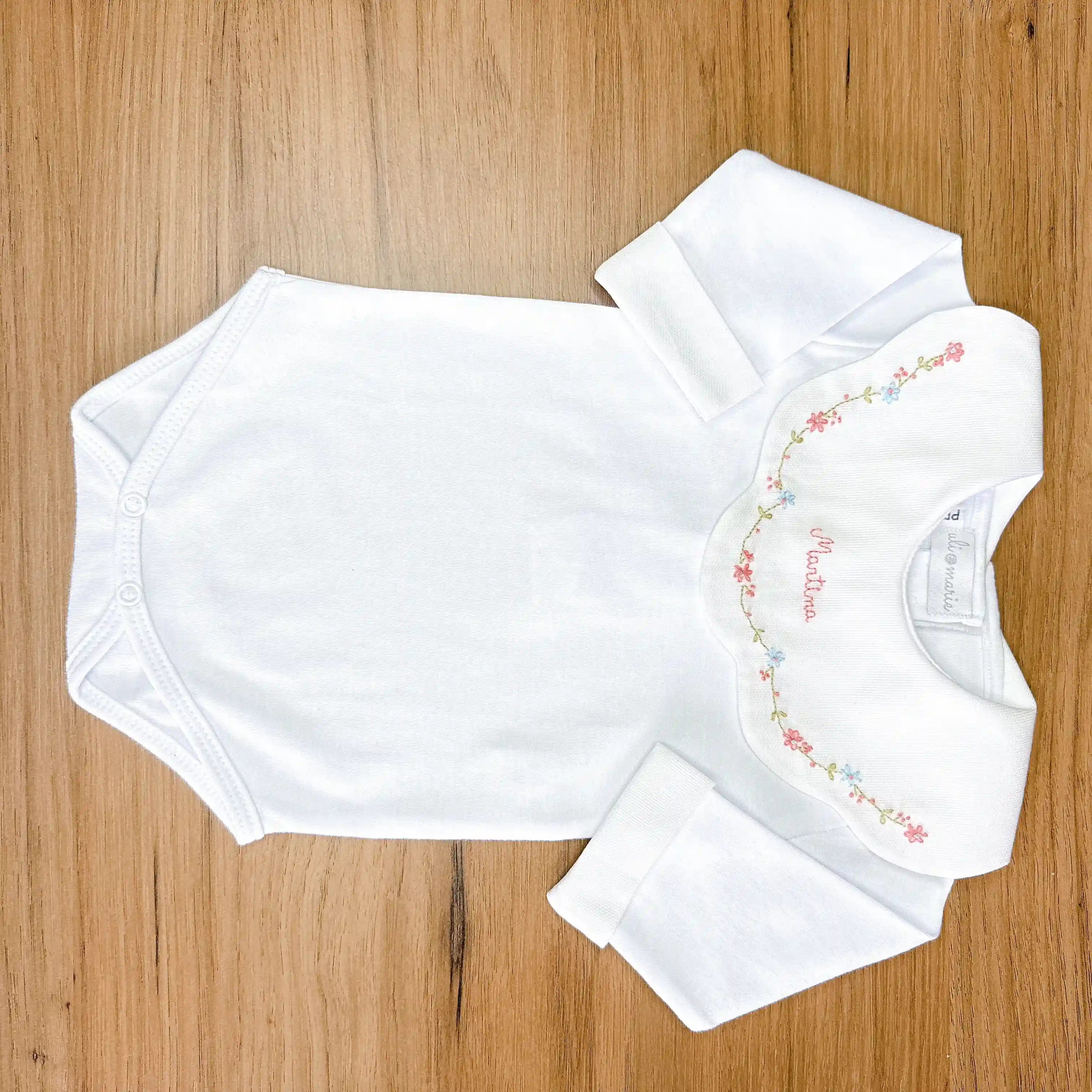 body encanto rosa e azul branco com gola bordada em flores rosa e azul e nome martina bordado