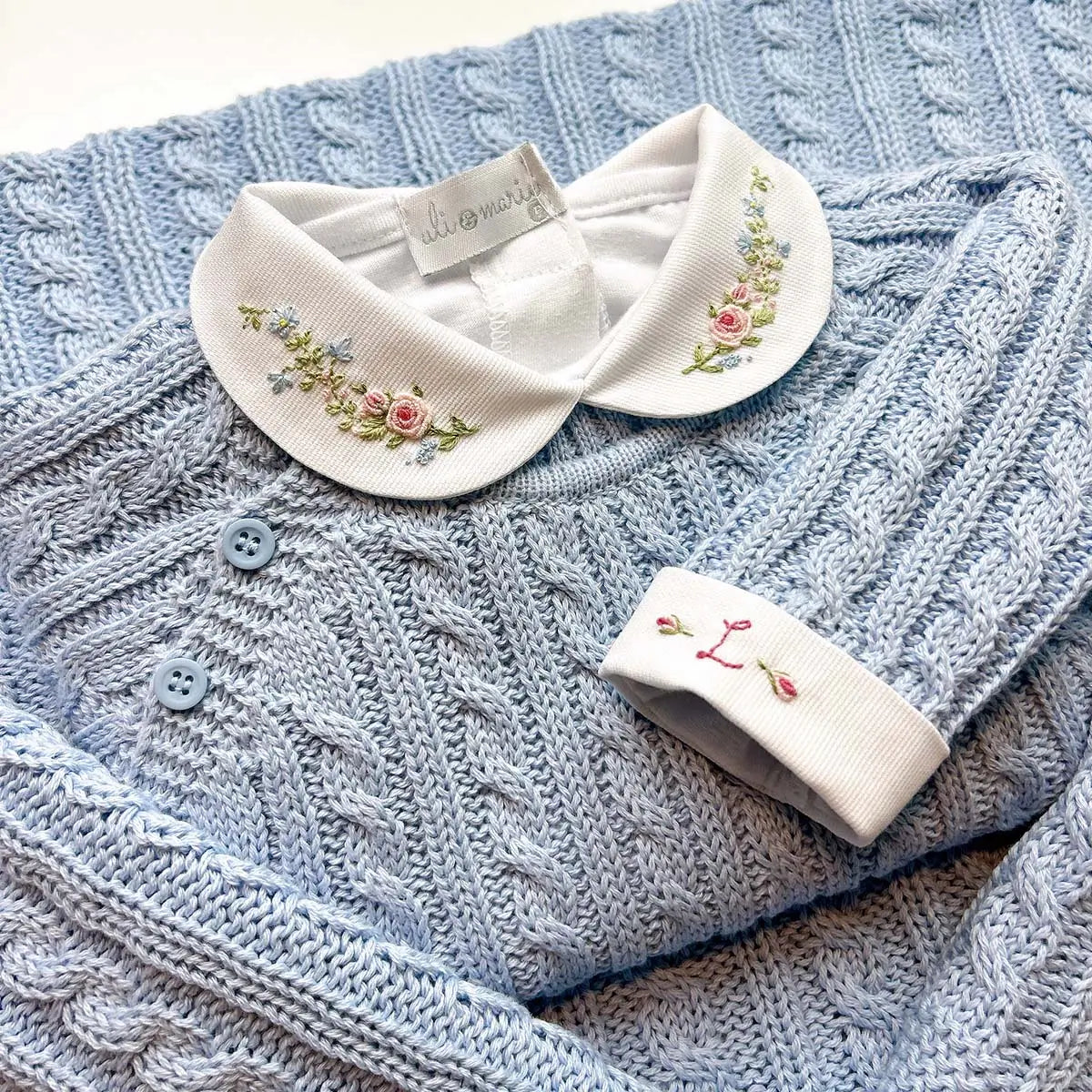 body delicatto branco de manga longa com punhos dobrados, e gola redonda bordada com flores em tons pastel