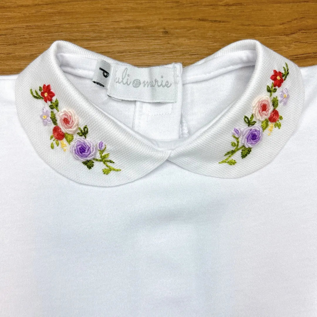 body lilac, modelo branco com gola bordada em flores coloridas nos tons de lilás, rosa e verde, confeccionado em algodão macio para o máximo conforto do bebê
