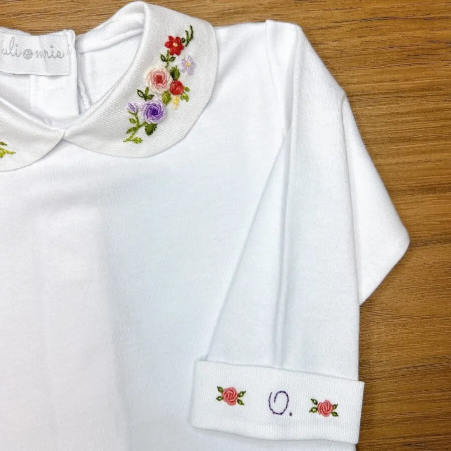 body lilac, modelo branco com gola bordada em flores coloridas nos tons de lilás, rosa e verde, confeccionado em algodão macio para o máximo conforto do bebê