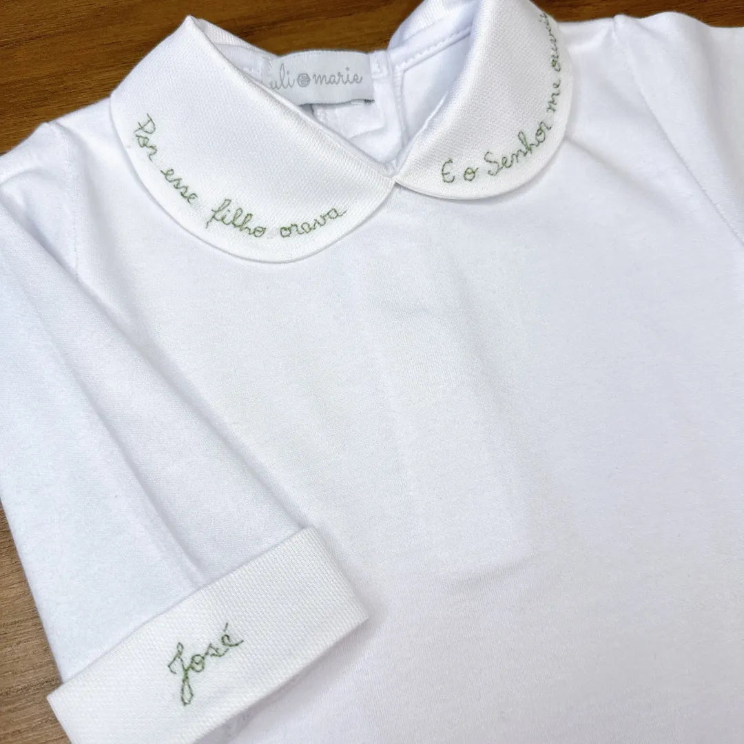 body milagre branco com gola peter pan bordada em vermelho com frase religiosa e detalhe de botão vermelho no punho