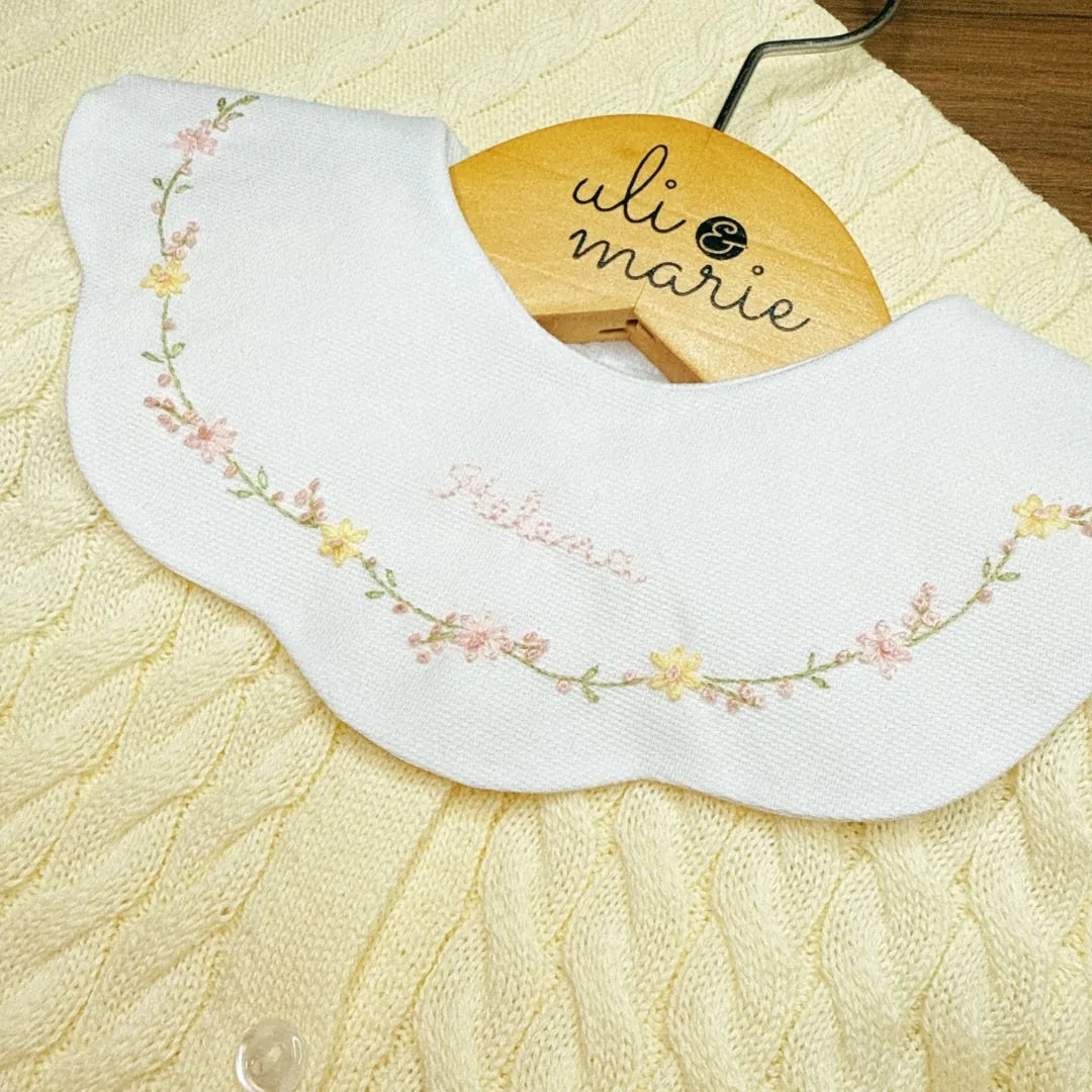 detalhe do body encanto amarelo bebê com gola peter pan bordada com flores e nome helena no centro