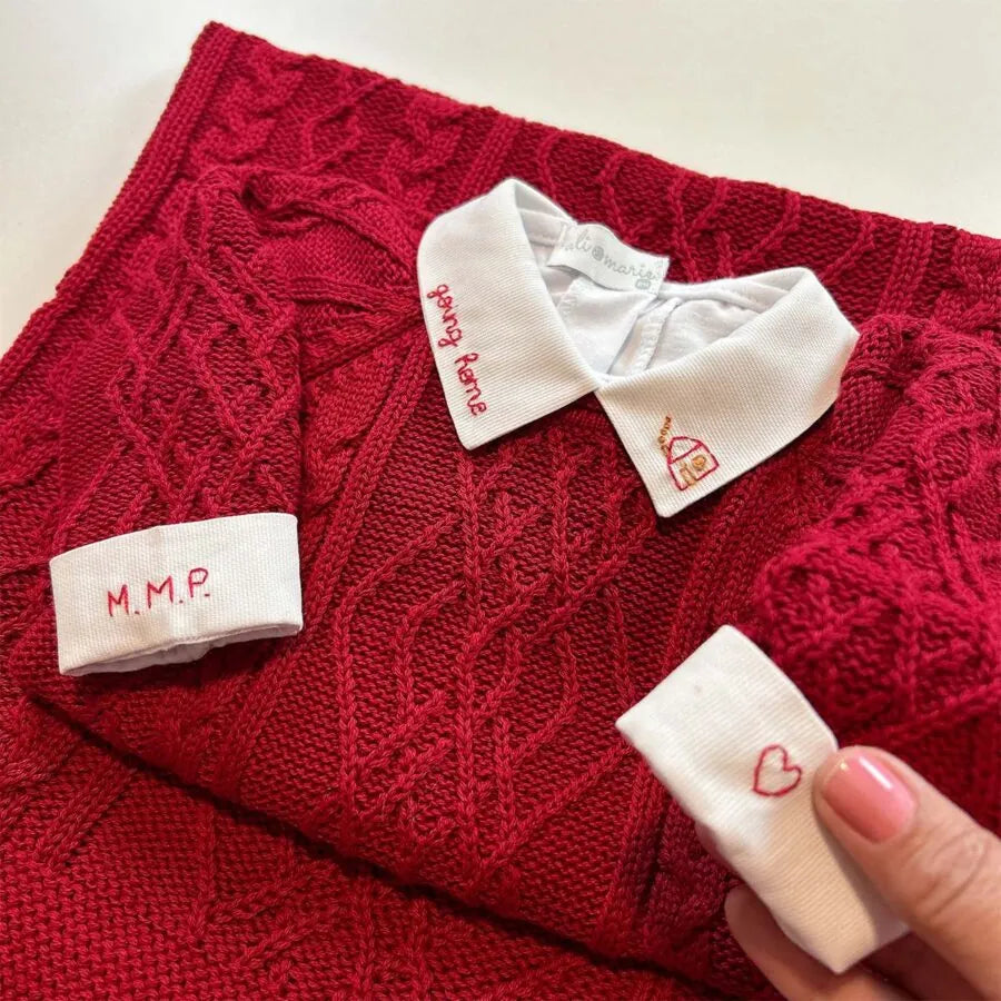 detalhe do body de tricô azul marinho com gola branca bordada com nome e foguete e punho monogramado