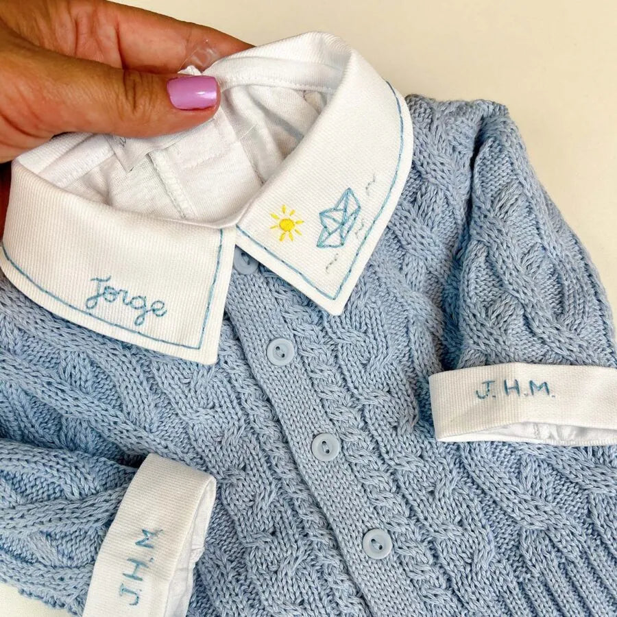 detalhe do body de tricô azul marinho com gola branca bordada com nome e foguete e punho monogramado