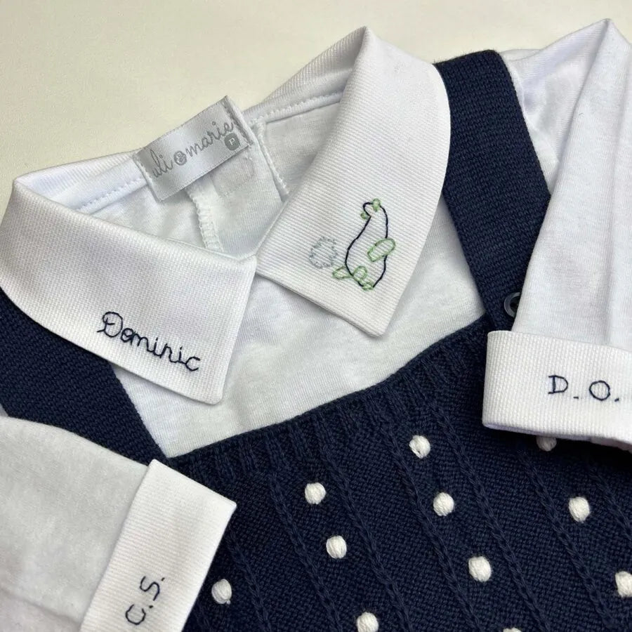 detalhe do body de tricô azul marinho com gola branca bordada com nome e foguete e punho monogramado