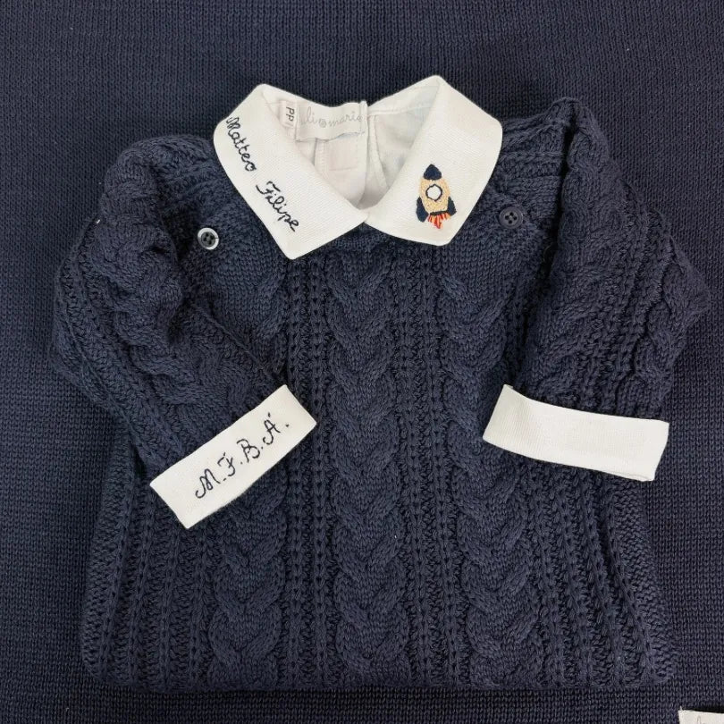detalhe do body de tricô azul marinho com gola branca bordada com nome e foguete e punho monogramado