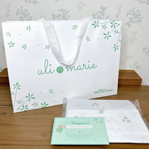 embalagem para presente uli & marie em papel branco com alças de fita e estampa verde de flores pequenas  
