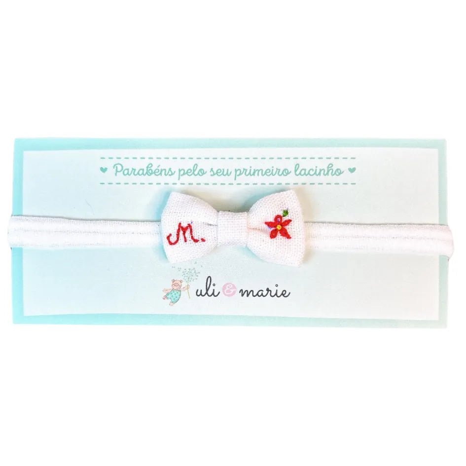 faixa de cabelo personalizada branca com laço bordado em vermelho e inicial decorativa ao lado