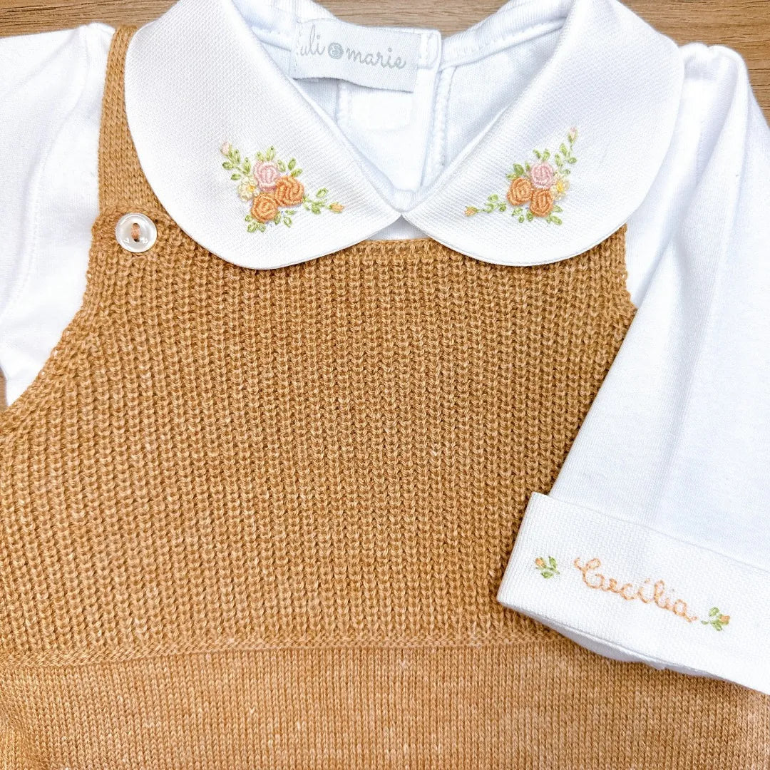 jardineira bambu caramelo de tricot, com body branco floral personalizado e pés fechados, conjunto para bebê em fundo isolado