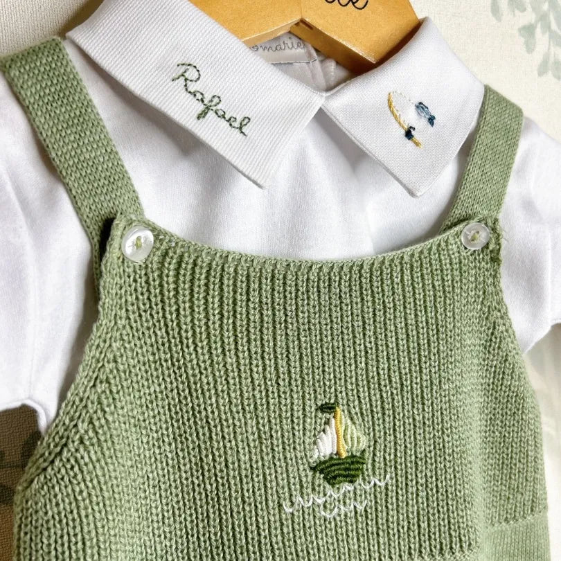 jardineira pescador em tricô sobre body branco manga longa, com bordado de barquinho e nome personalizado