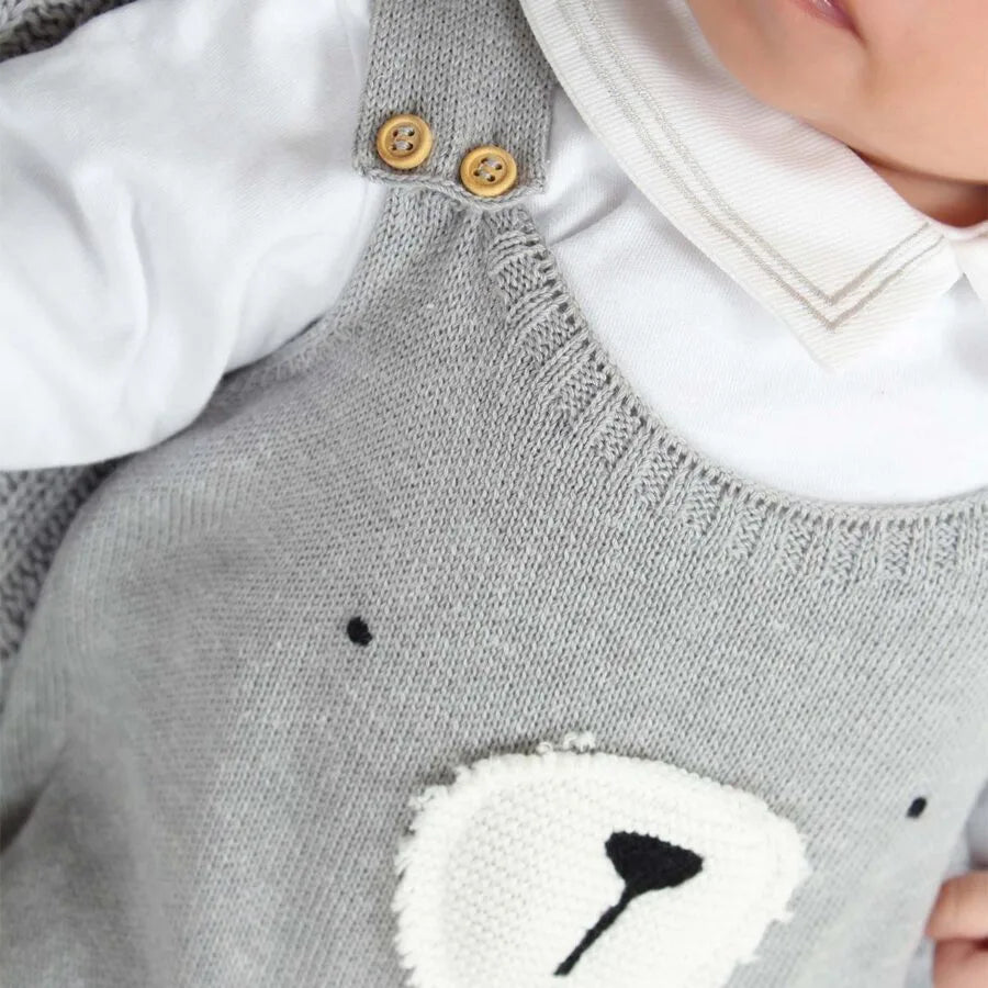 jardineira teddy cinza de tricô com body branco de manga longa, detalhe de rosto de urso bordado no peito