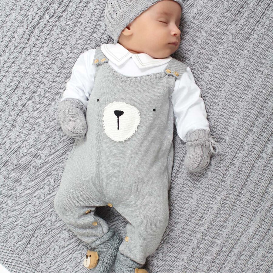 jardineira teddy cinza de tricô com body branco de manga longa, detalhe de rosto de urso bordado no peito