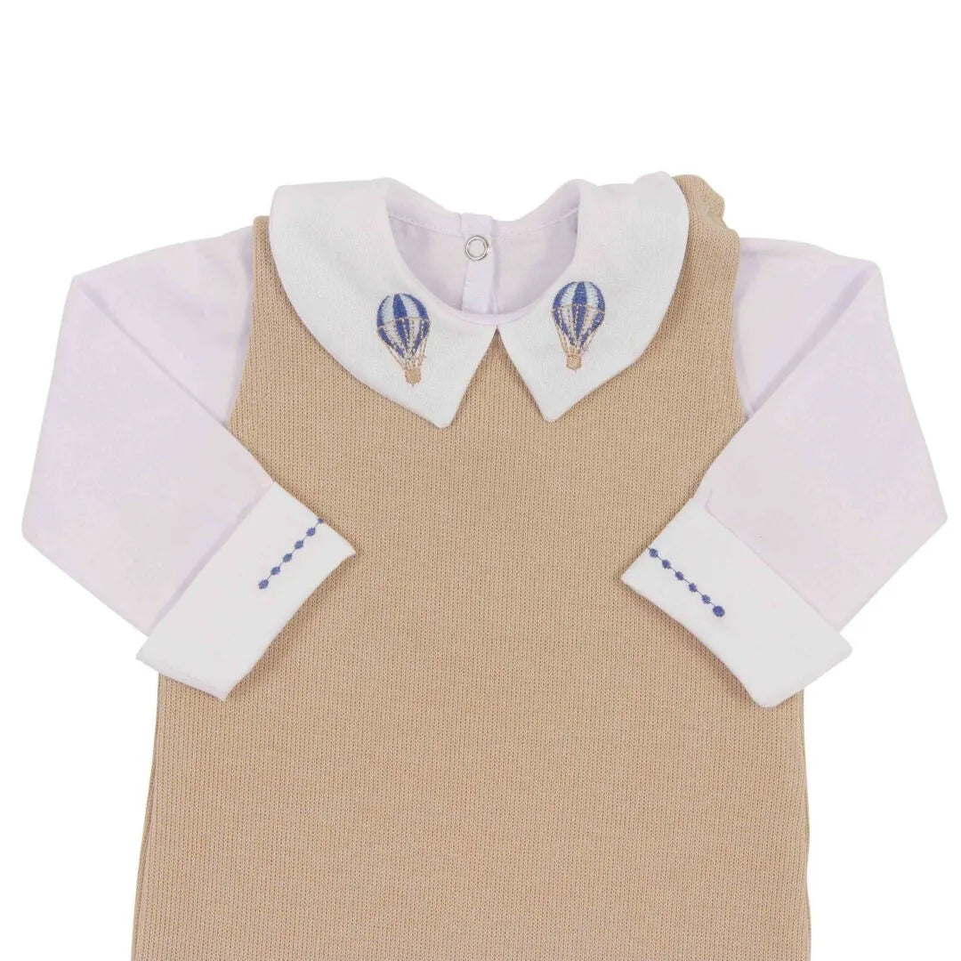 detalhe da gola balão azul do body branco por baixo da jardineira de tricô bege, exibindo bordados de balões