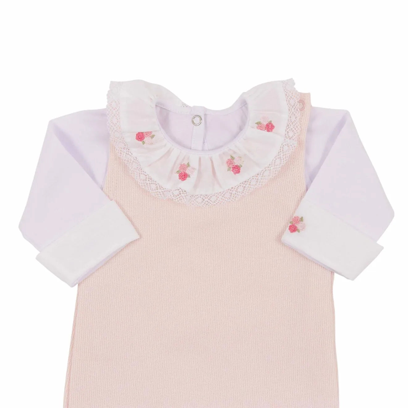 close-up do conjunto: body branco de manga comprida por baixo da jardineira de tricô rosa claro com gola bordada de flores