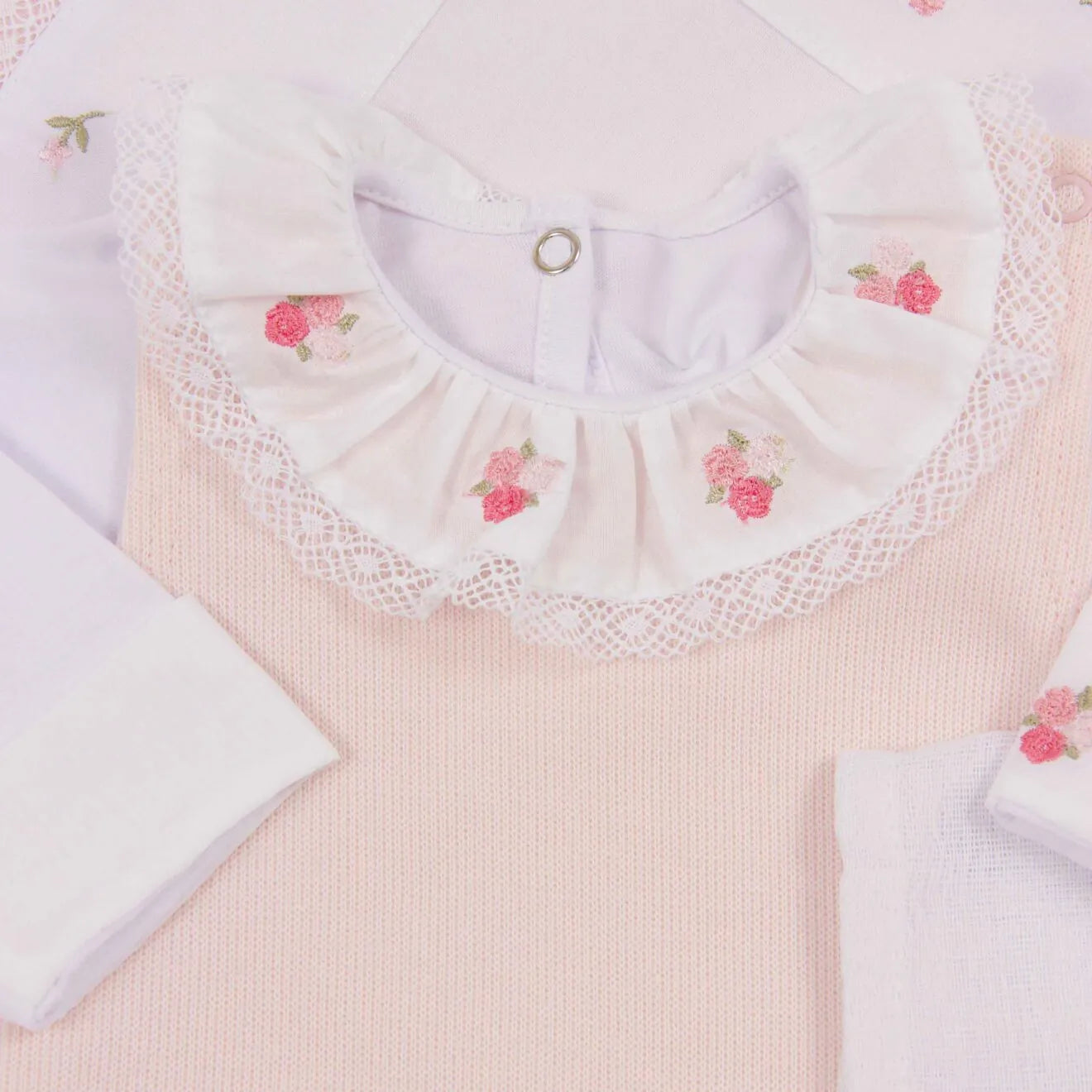 detalhe da gola babado rendada e bordada com pequenas rosas na jardineira de tricô rosa, mostrando a delicadeza do acabamento