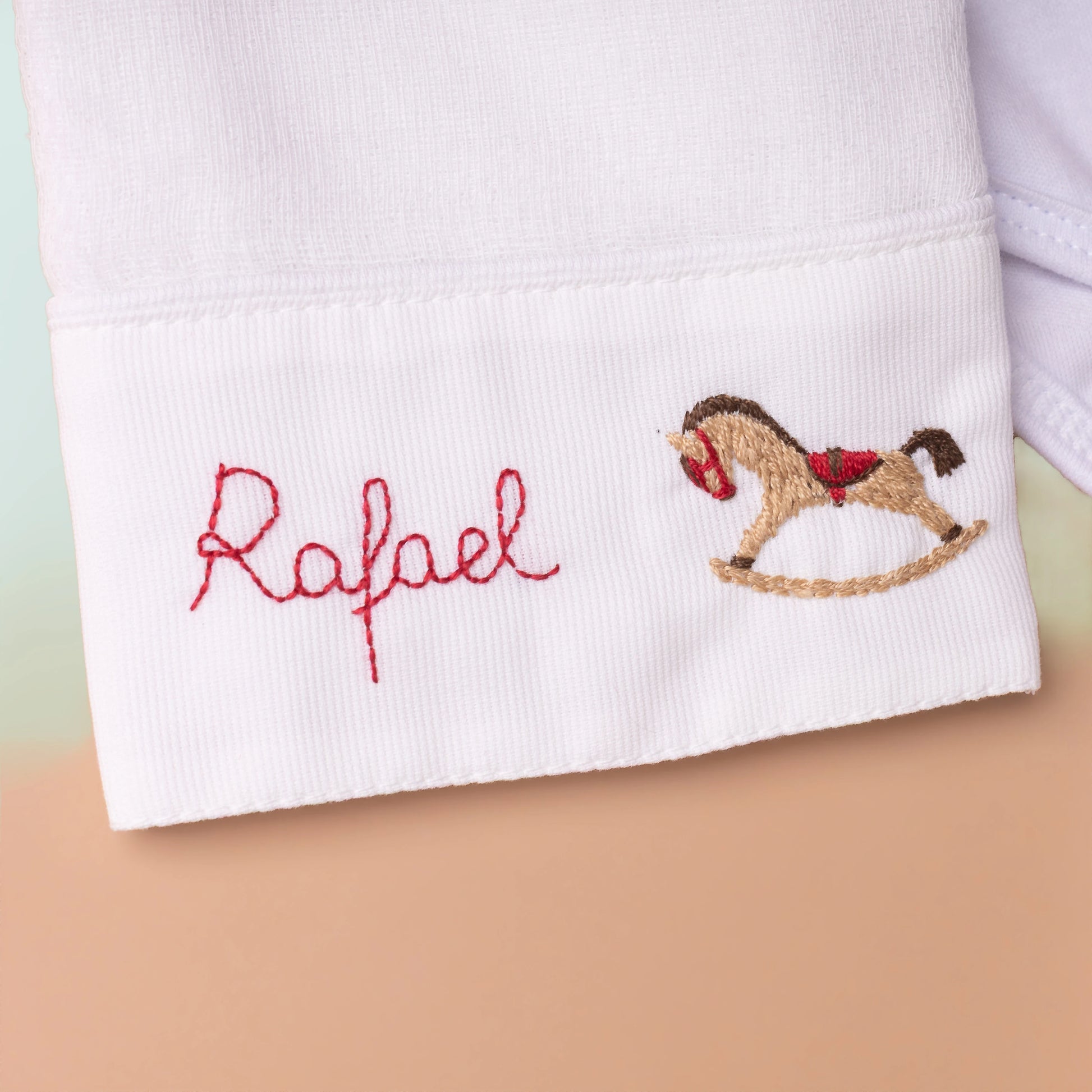 Bainha da calça branca com bordado 'Rafael' e aplique de cavalo
