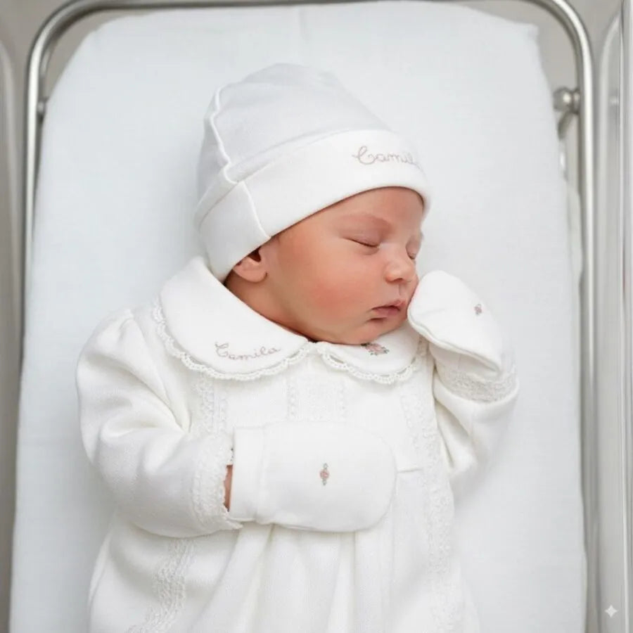 Kit Maternidade Cecília Personalizado off-white com bebê deitado vestindo macacão rendado e luvas bordadas