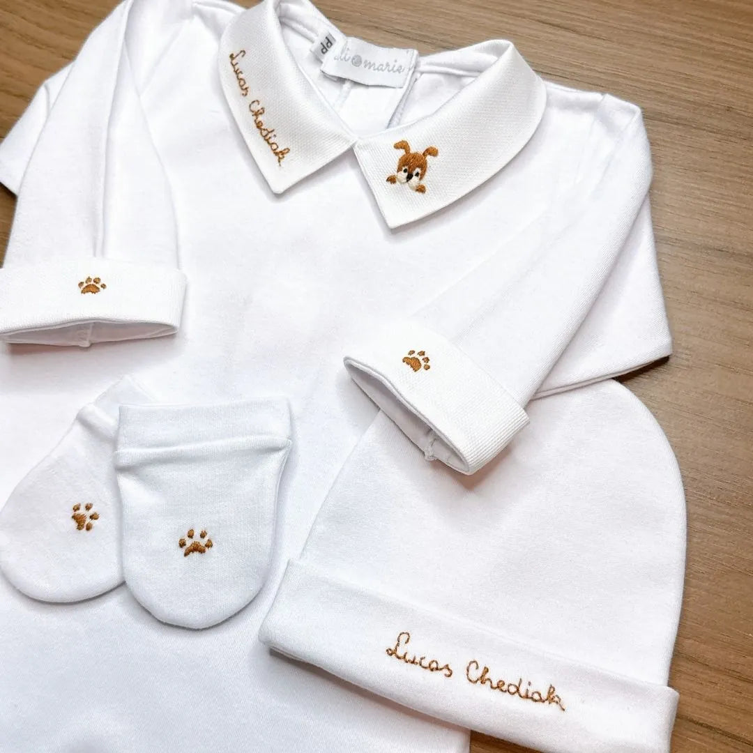 close-up de três peças do kit maternidade dog personalizado: body com gola bordada, touca e luvas brancas