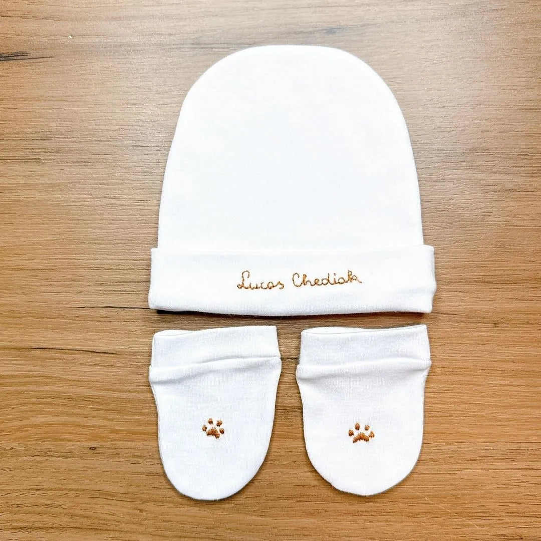touca e luvas brancas do kit maternidade dog personalizado. touca com o nome 'lucas chediak' e luvas com bordado de pata