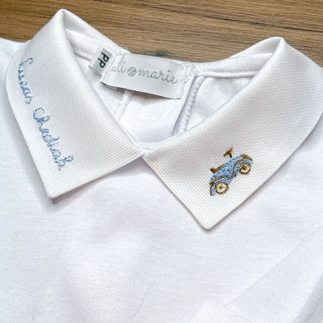 detalhe do conjunto com touca e punhos mostrando iniciais bordadas em azul claro sobre o algodão branco