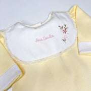 Macacão amarelo claro com gola branca e bordado manual feito à mão com nome e flores delicadas