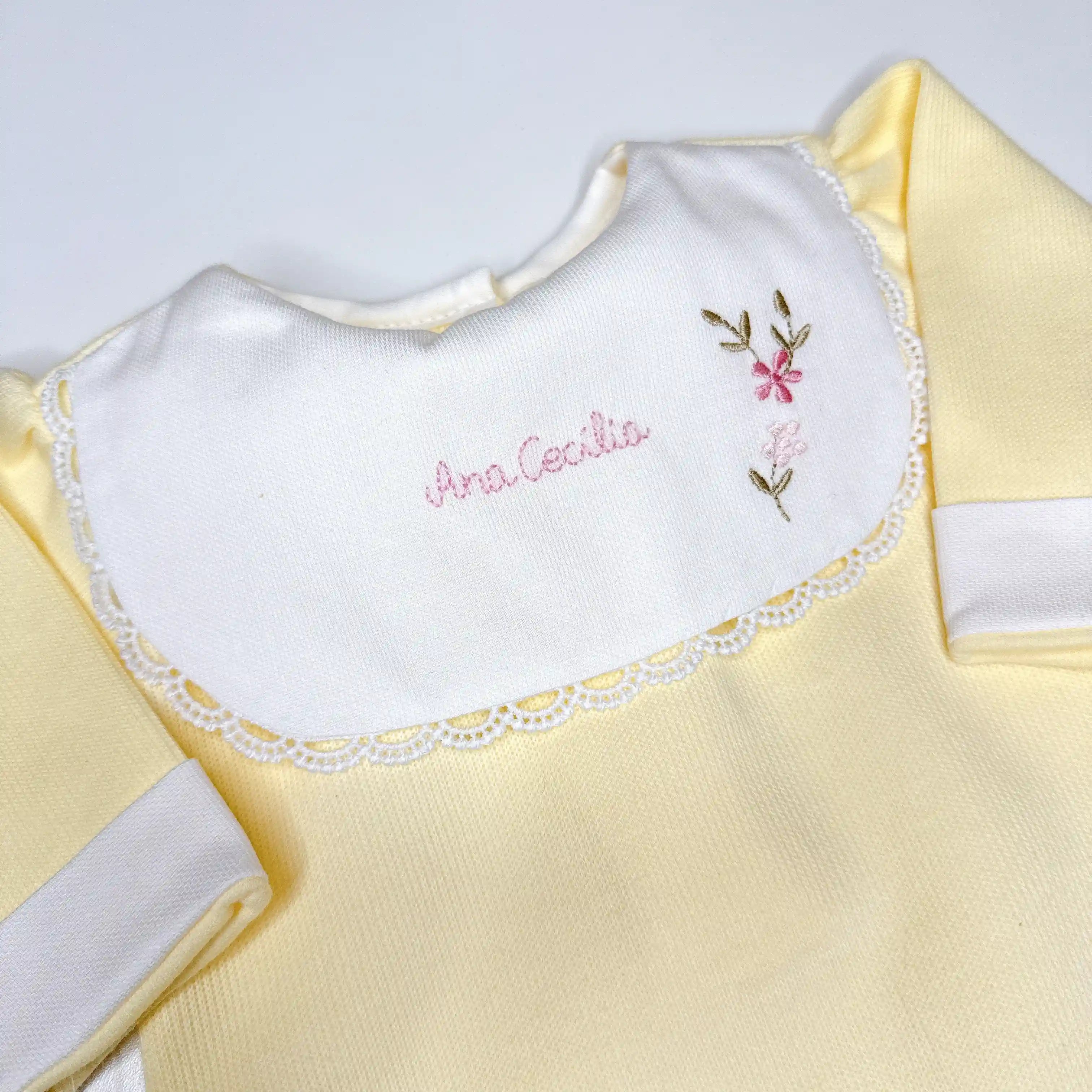 Macacão amarelo claro com gola branca e bordado manual feito à mão com nome e flores delicadas