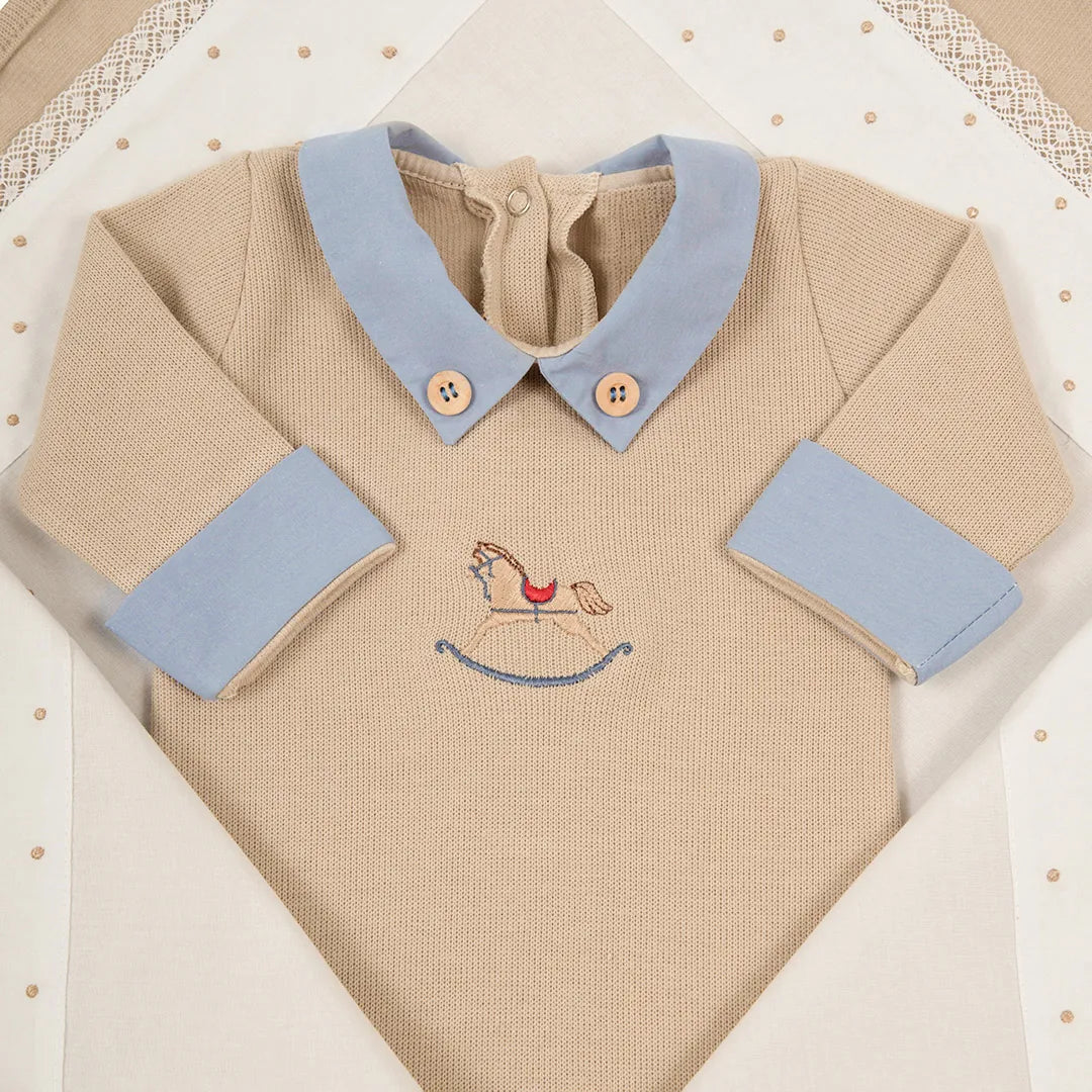 macacão horse bege e azul em algodão, com bordado de cavalo, posicionado sobre uma manta branca e creme texturizada