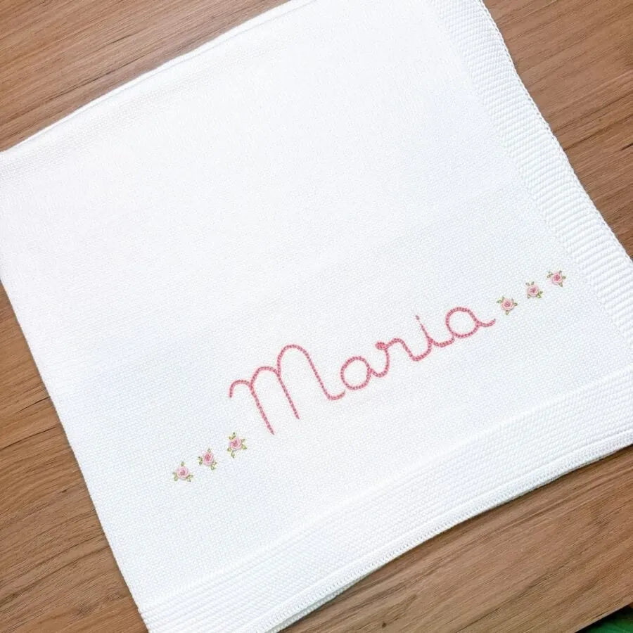 manta básica personalizada, confeccionada em tricô macio com nome bordado e delicados detalhes florais, perfeita para aconchegar o bebê com carinho e exclusividade