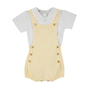 romper capri amarelo bebê com botões de madeira e body branco básico de gola polo sobre fundo isolado