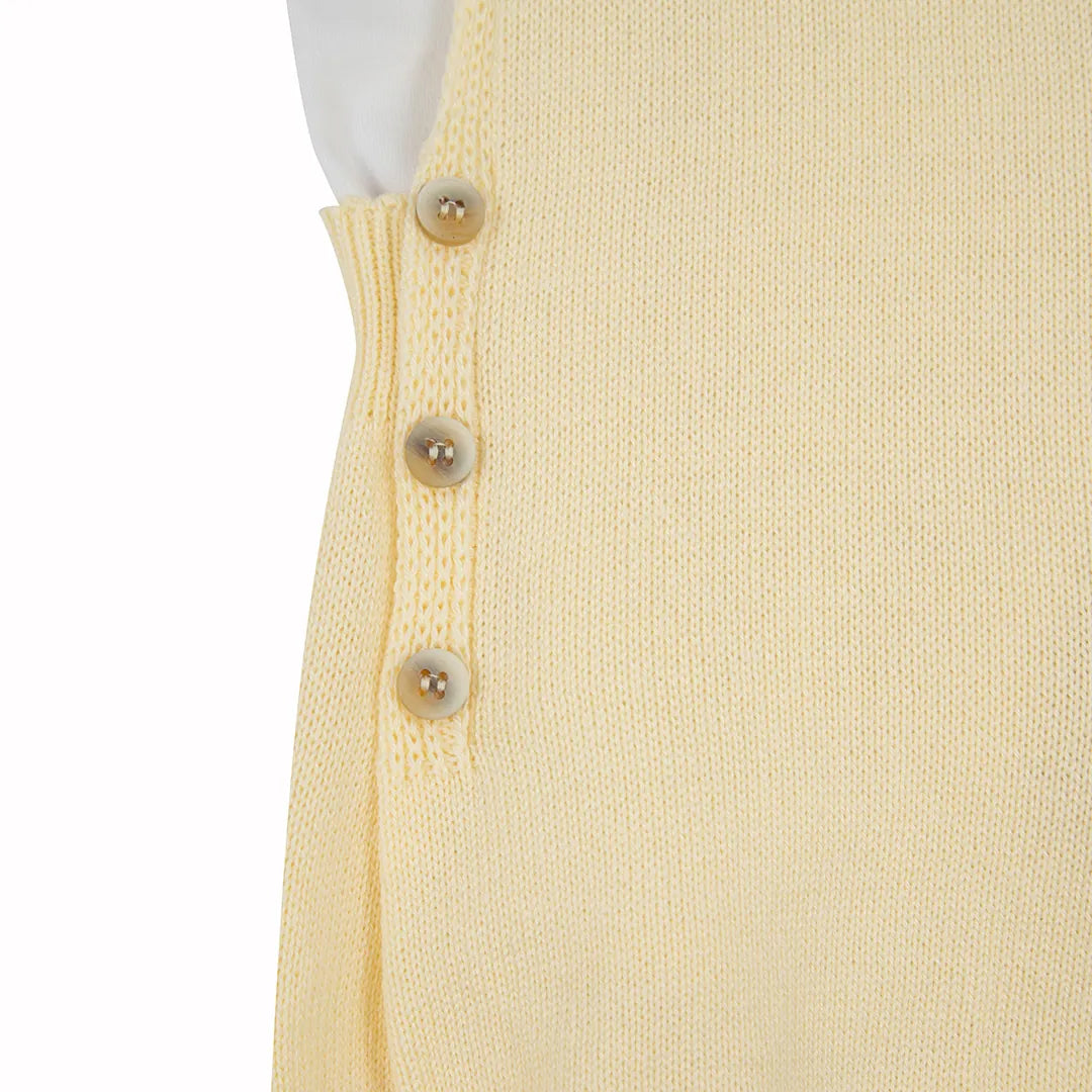 romper capri amarelo bebê com botões de madeira e body branco básico de gola polo sobre fundo isolado