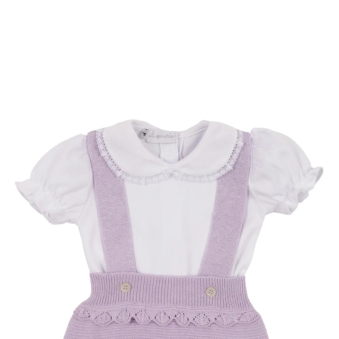 romper malu lilás com barra e cintura onduladas e suspensórios, sobre body branco com gola de renda
