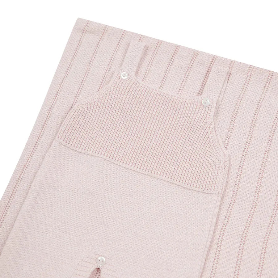 saída maternidade bambu rosa bebê com jardineira de tricô em frente a manta com detalhes em listras verticais