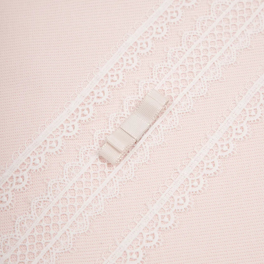 close-up da manta cecília rosa bebê, destacando a textura do tricot e o detalhe das rendas brancas e laço central aplicado