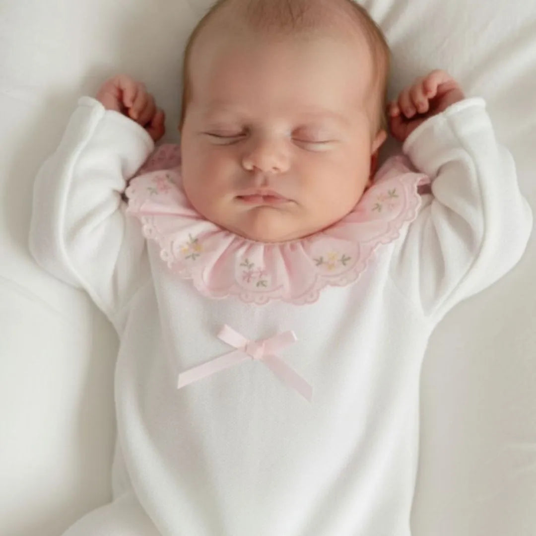 bebê vestindo macacão melina off-white com gola babado rosa bordada e laço delicado
