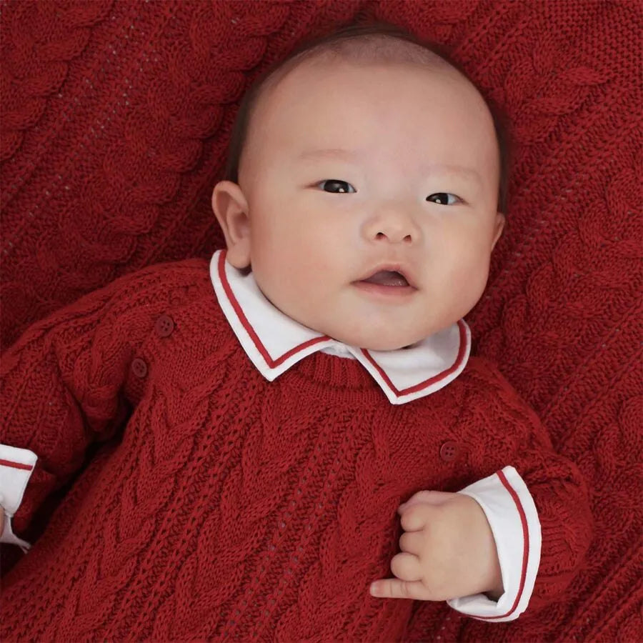 saída maternidade sorrento vermelha composta por macacão em tricô com padrão trançado e manta combinando, perfeita para o primeiro look do bebê