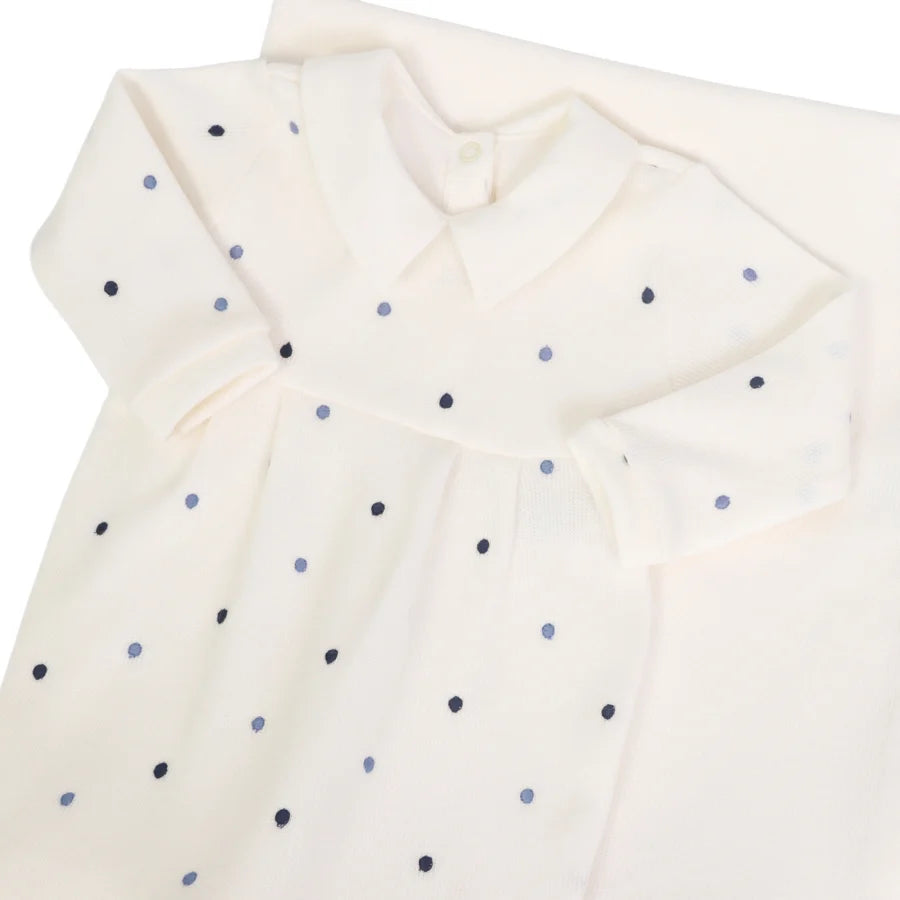 Macacão off-white com poás azul marinho e azul claro, gola lisa, compondo o conjunto com a manta