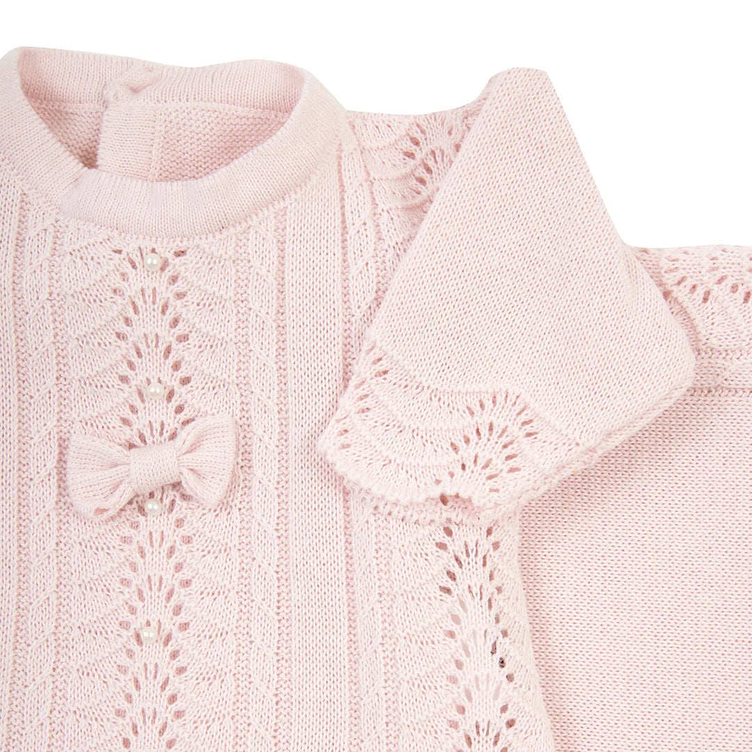 detalhe do peito do macacão de vestido rendado rosa, mostrando a sobreposição da renda e o mini laço